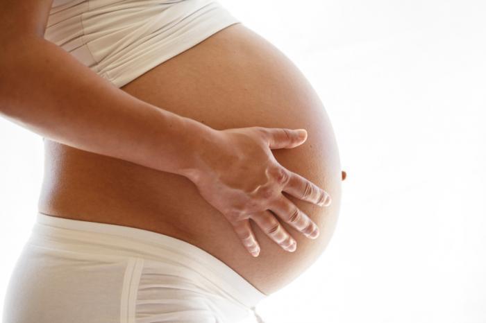 mulher grávida com as mãos na barriga