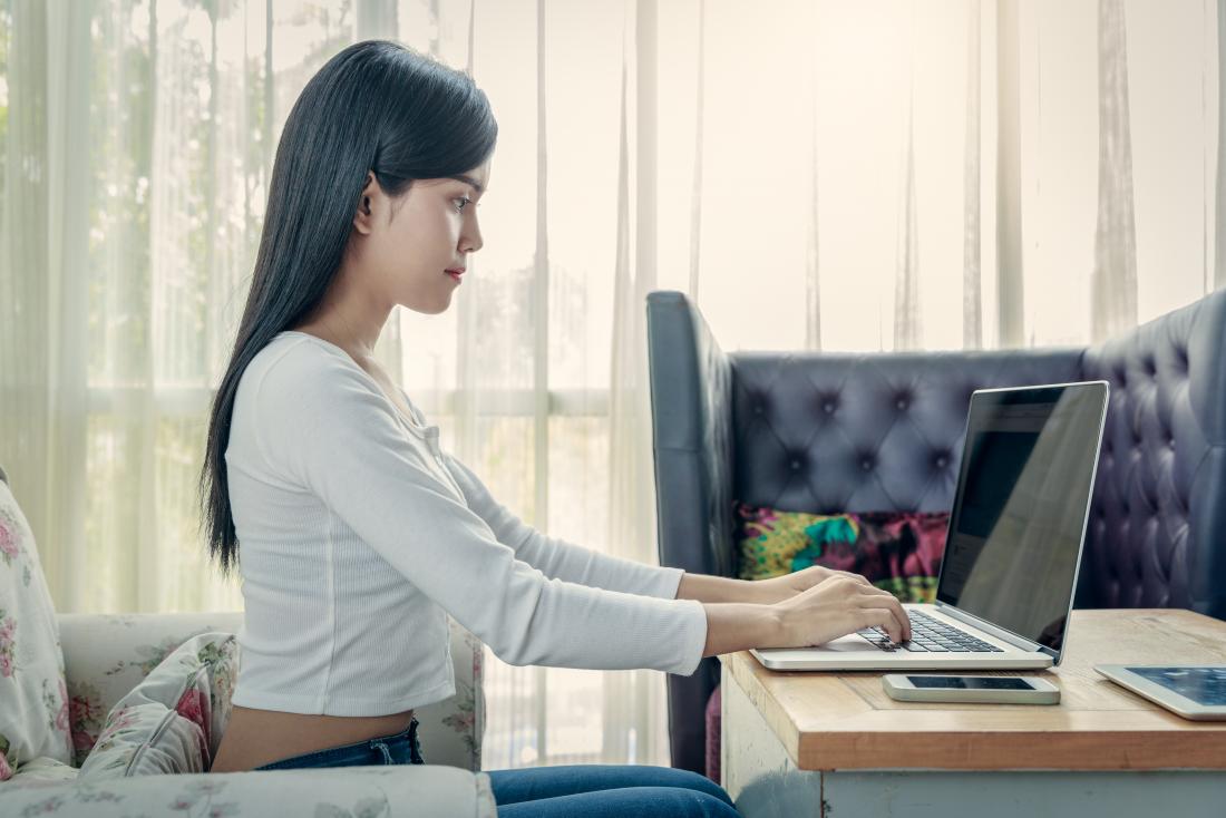 Posições sentadas para uma boa postura 1 Posição sentada para uma boa postura com a mulher sentada em linha reta digitando no laptop.