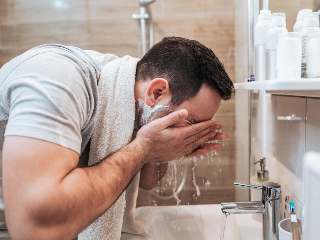 um homem lavando o rosto para evitar poros no nariz