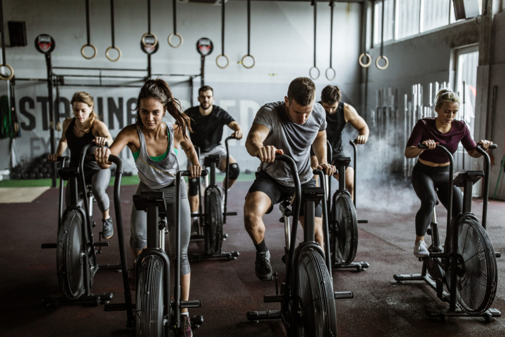Homens e mulheres em bicicletas ergométricas